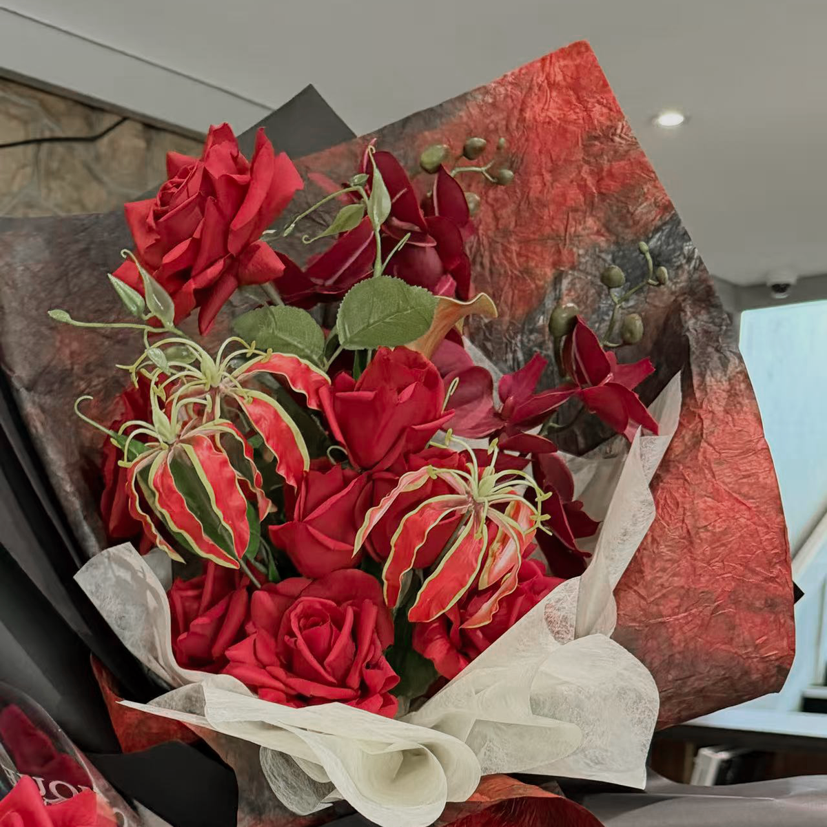 Red bouquet with roses, gloriosa and a white calla lily