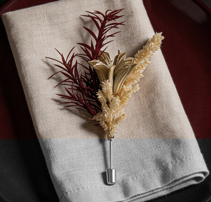 Burgundy and cream preserved flower brooch laid on folded fabric