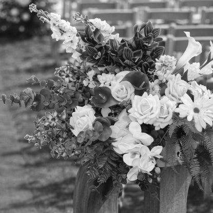 Black-and-white client photo of a large mixed floral arrangement being held