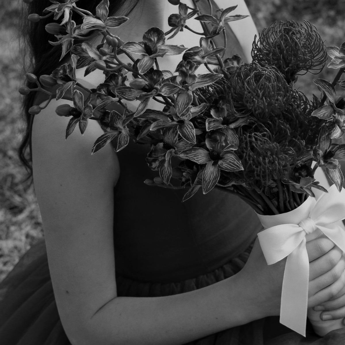 Dark-toned artificial flower bouquet tied with a white ribbon