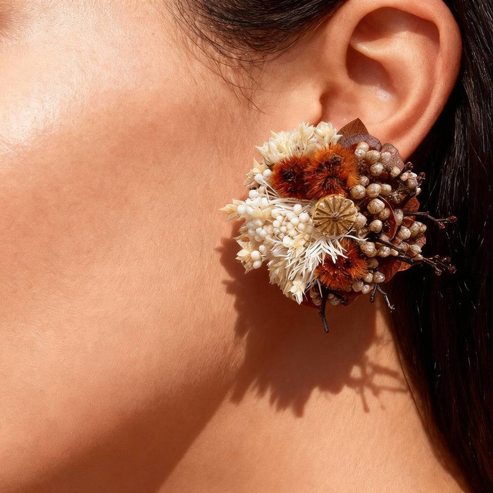 Cream, rust and brown preserved flower clip-on earring worn on an ear